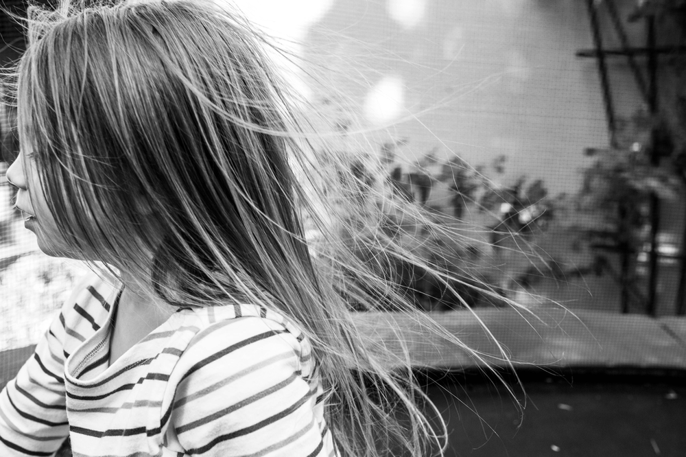 black and white image of a little girl wearing a striped shirt with her hair blowing in the breeze
