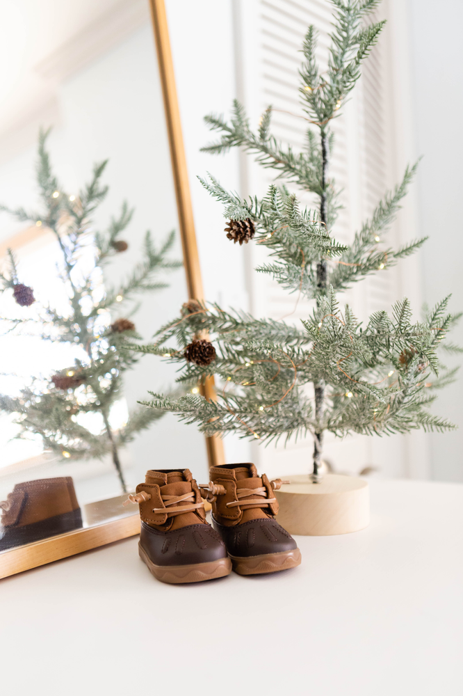 delicate sapling with fairy lights, baby duck boots, naturally framed mirror, California nursery decor