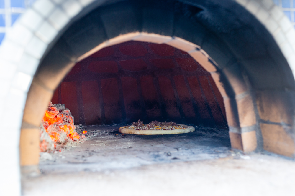 specialty pizza oven with hot glowing coals and a pizza inside