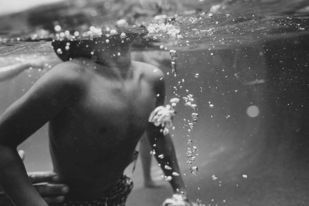 black and white image of a kid surfacing from the water