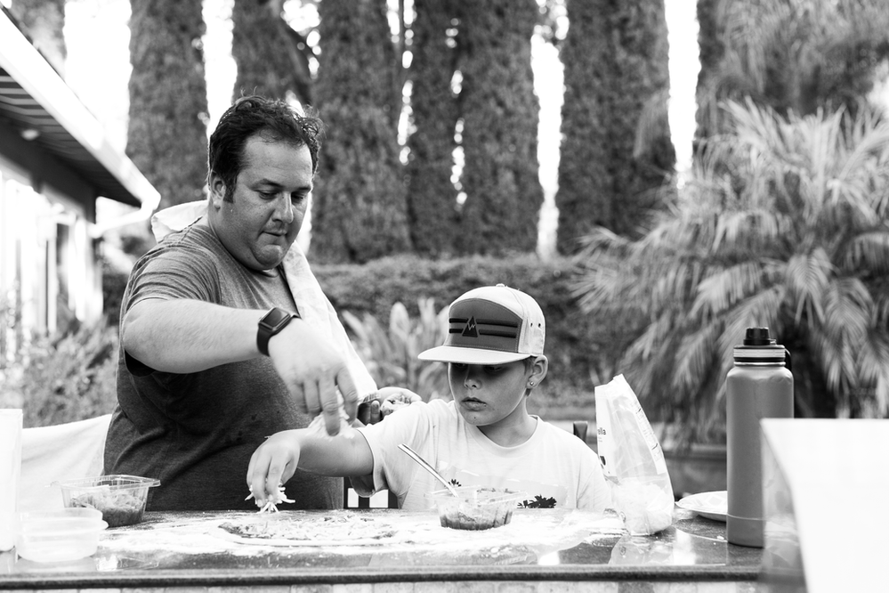 black and white image of an uncle and his nephew creating homemade pizza pies together