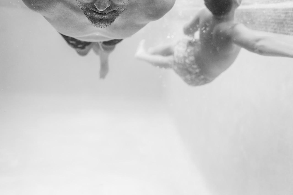 black and white image of a father and son swimming underwater