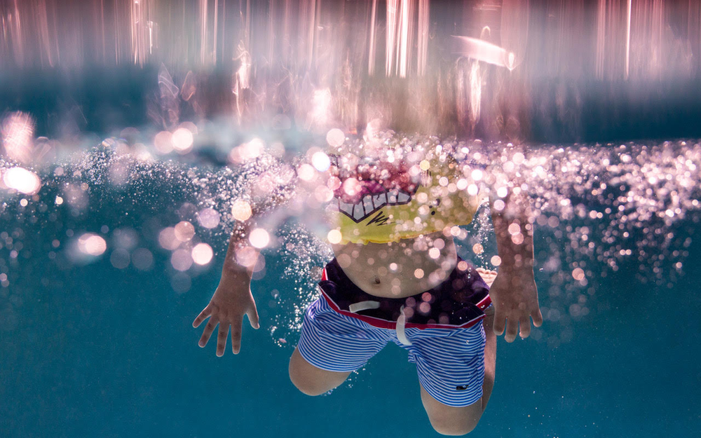 underwater image of a child splashing into a pool wearing a floatie